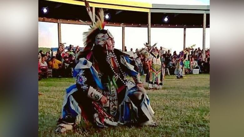 A man in regalia dances at a powwow.