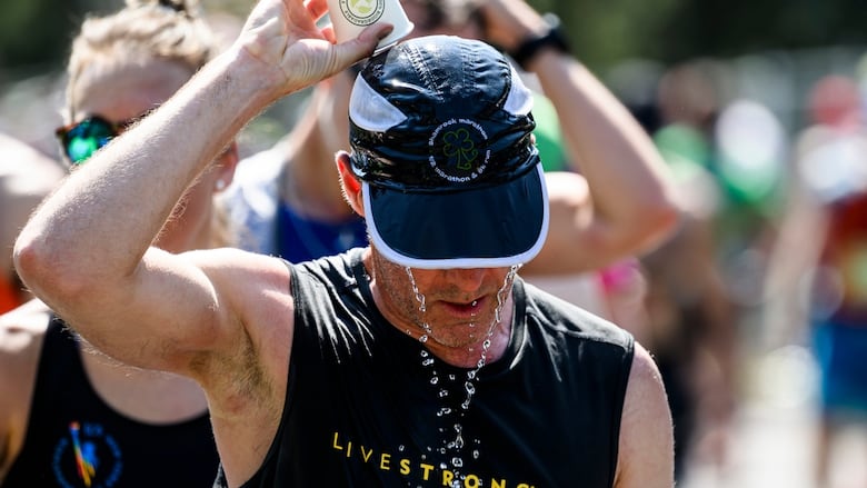 A man pours a water bottle over his head.