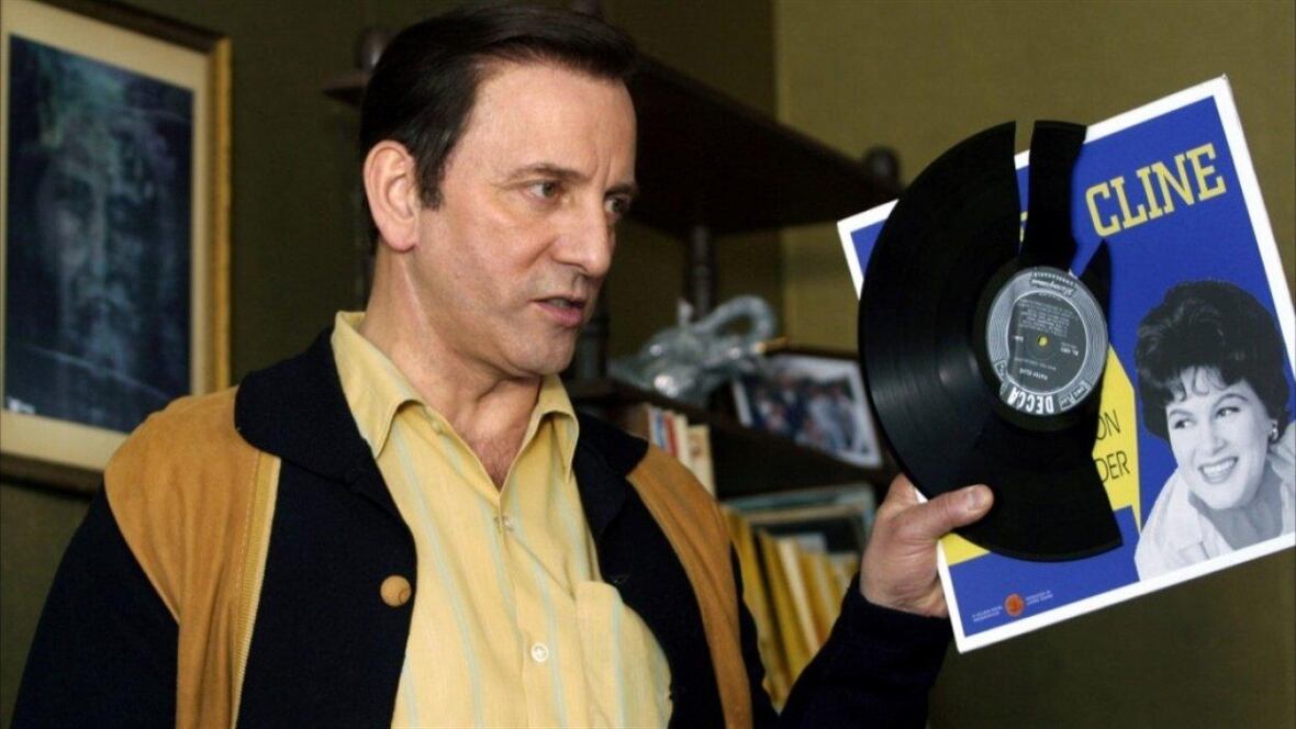 A man holds up a vinyl record.