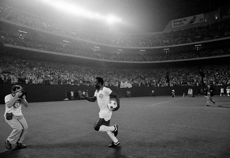 Pelé runs onto field, ahead of a soccer match in East Rutherford, N.J., on Aug. 25 1977.