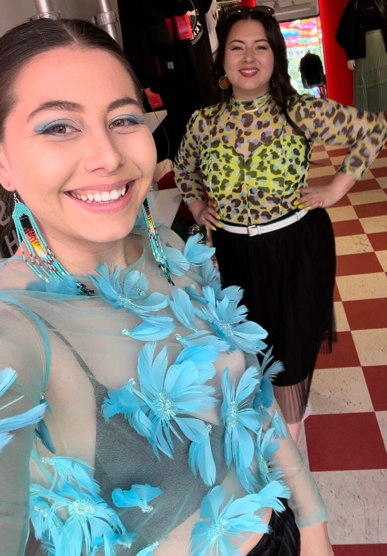 Two women, standing in store, smiling for a photo.