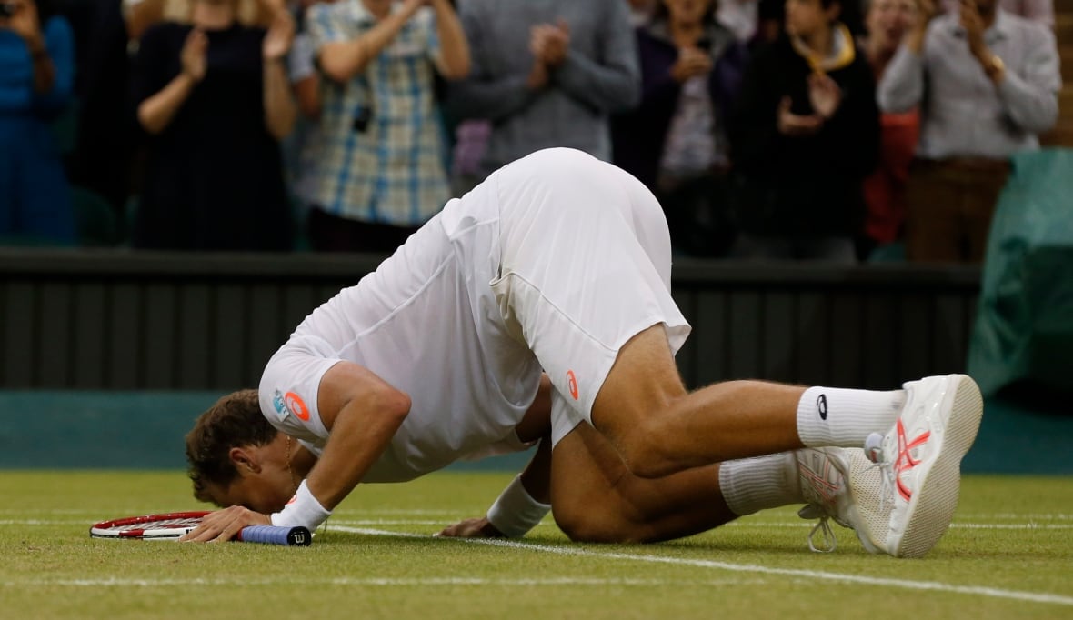 Vasek Pospisil kisses the turf at Centre Court, after winning Wimbledon's men's doubles in 2014