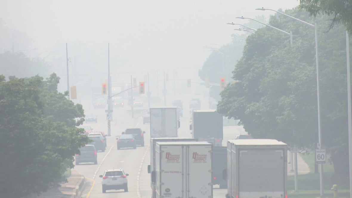 Heavy smoke is seen on a roadway with trucks.