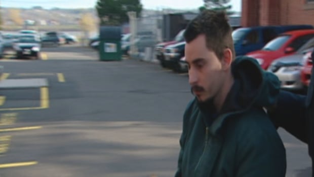 Gregory Despres is walked into the Fredericton courthouse as part of his first-degree murder trial in 2007. A man in a green jacket walks in a parking lot.
