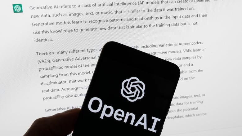 Phone screen that says "OpenAI" in front of ChatGPT displayed on a computer. 