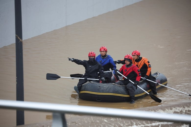 Rescuers paddle a rubber raft.