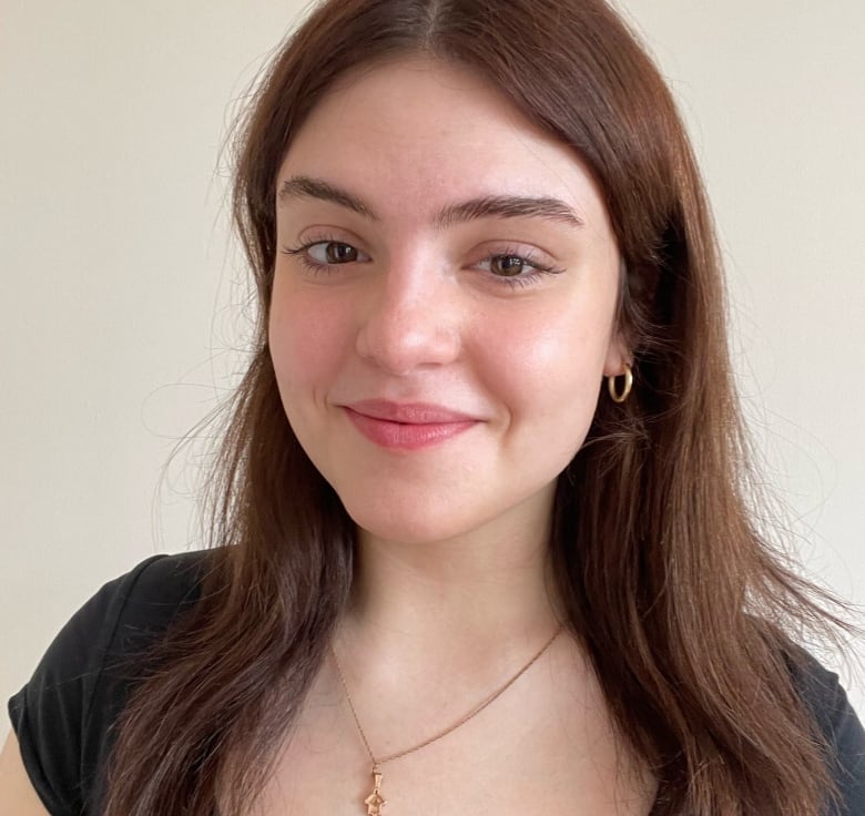 A head and shoulders photo of a young woman, wearing a black top and smiling at the camera. 