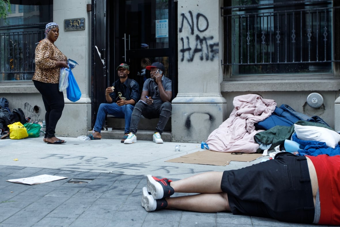 Asylum seekers from Africa and other locales are photographed outside of a shelter intake office at Peter St. and Richmond St. in Toronto, on July 14, 2023. A lack of Toronto shelter space has forced asylum seekers to sleep outside.
