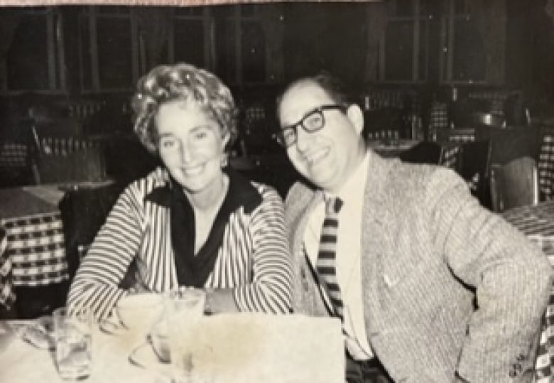 A black and while photo from the late 1950s or early 1960s of a man and a woman sitting at a restaurant table.