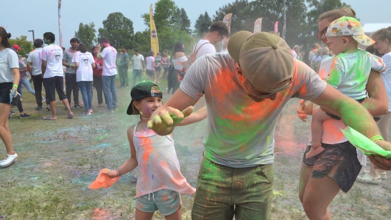 A young child throws powder at a man, who is smiling.