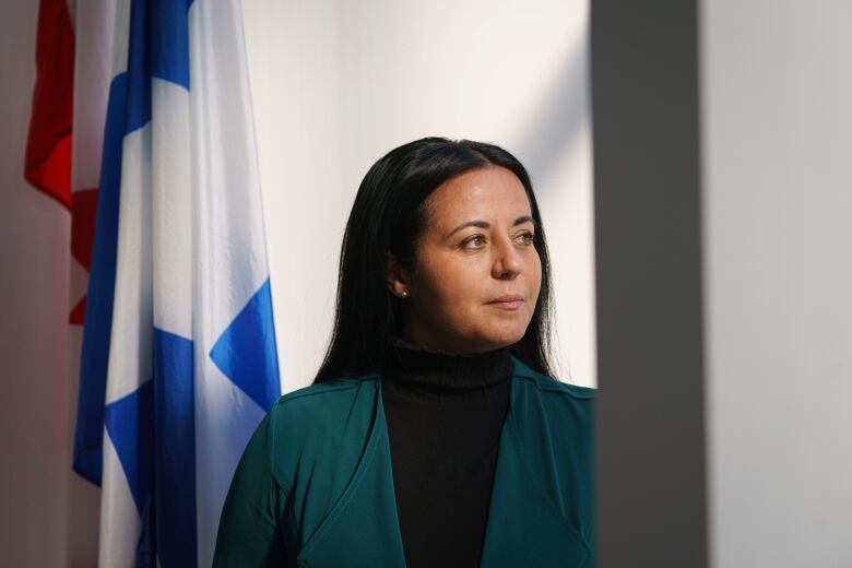 A woman looking to the side in front of two flags.