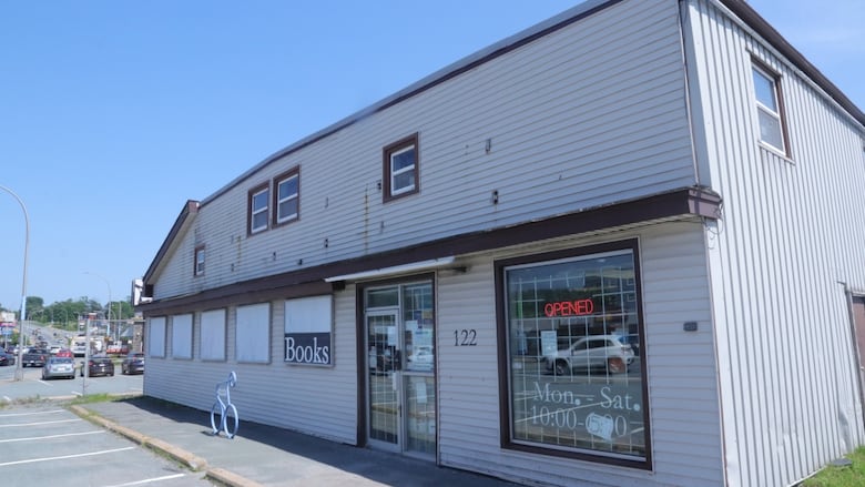 A white building, with vinyl siding, that houses John W Doull's book store.