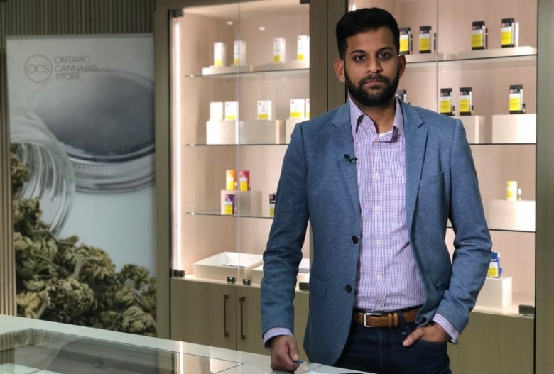 Photo of David Lobo standing in front of some cannabis products on shelves. 