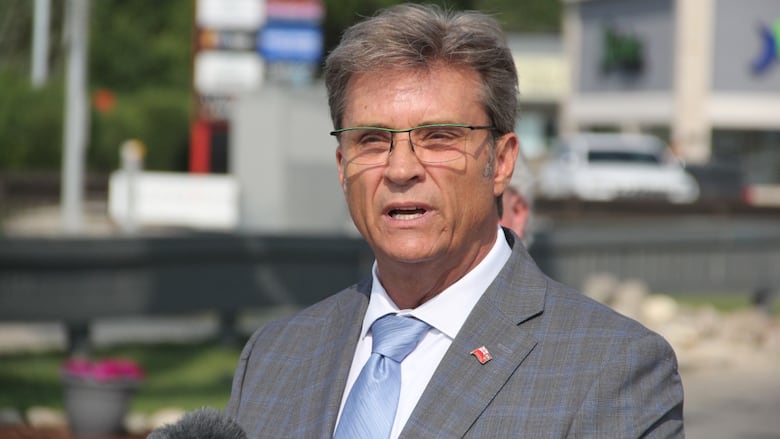 A man in a suit and tie speaks into a microphone.