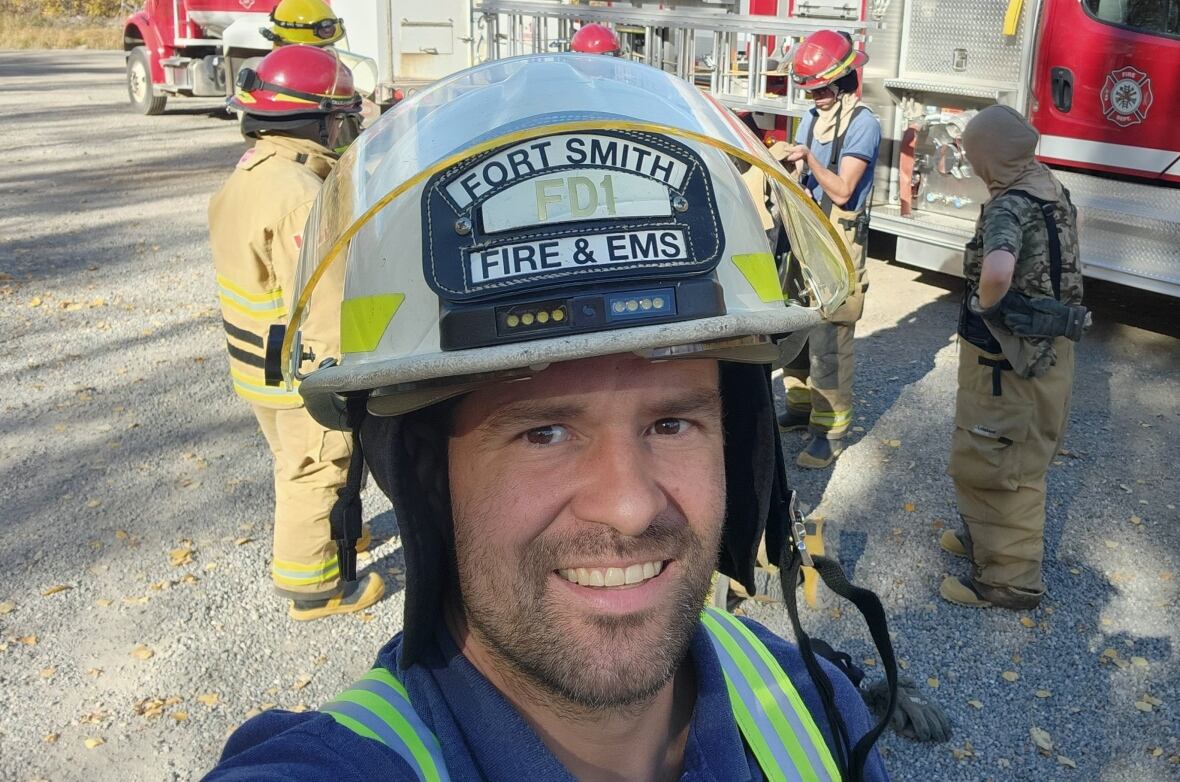 A man smiling in a fire Fort Smith EMS hat