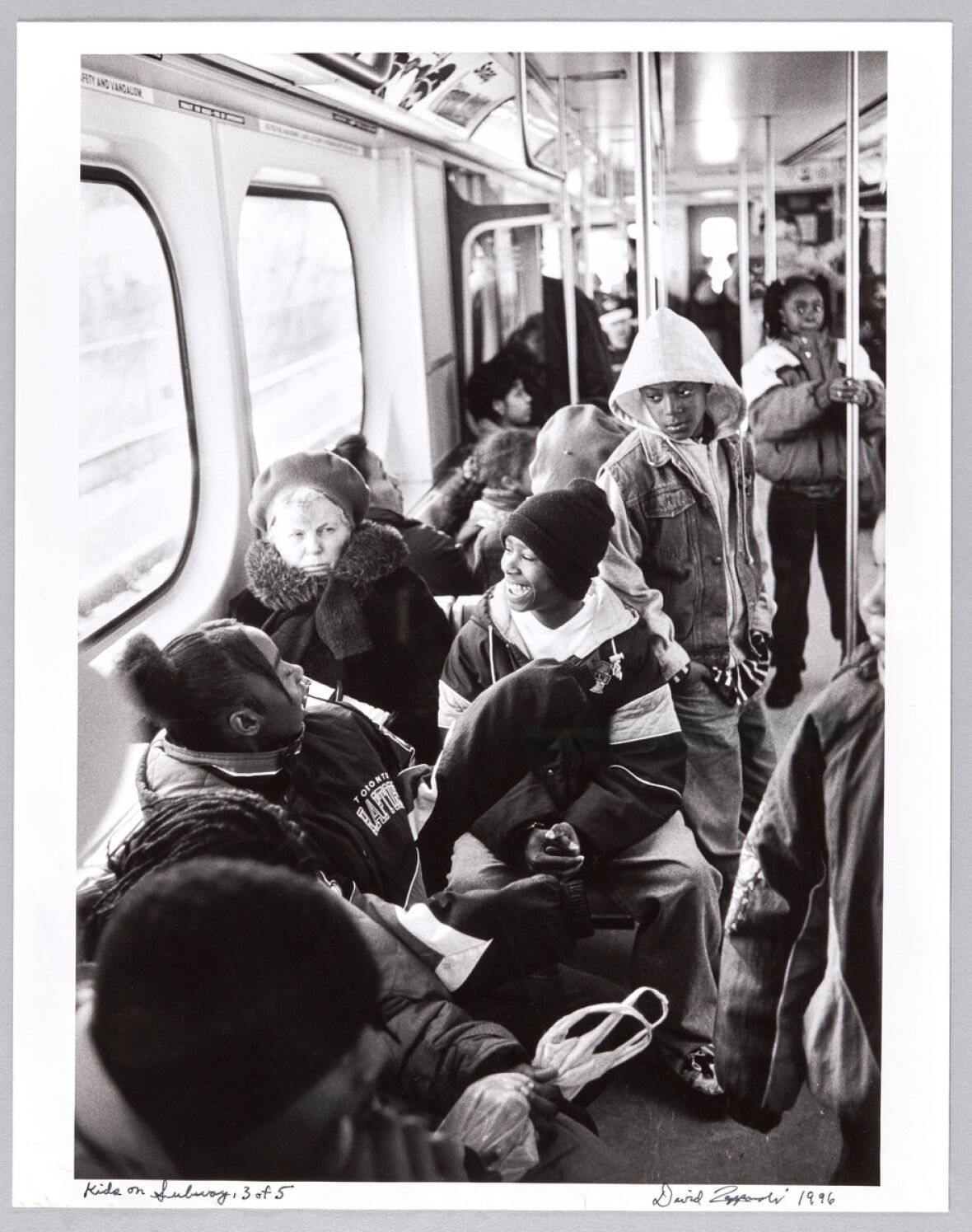 Several teenagers and one older woman on a subway.