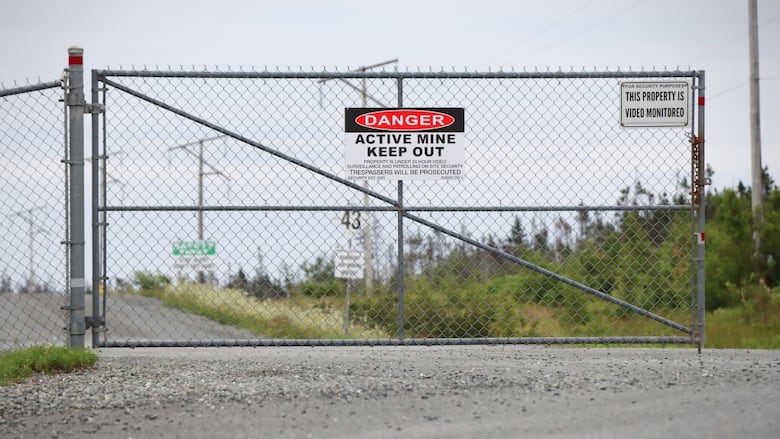 A chain link gate is shown with a sign saying 'Danger Active Mine Keep Out.'