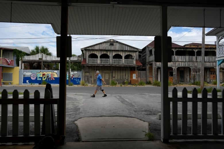 An old town street with wooden structures and a man walking by 