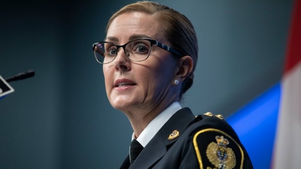 A white woman wearing a police uniform looks at the camera.