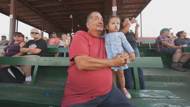 Searching for solace a year after tragedy in James Smith Cree Nation; Darryl Burns and his two-year-old granddaughter, Parker, watch chariot races in Prince Albert, Sask\.