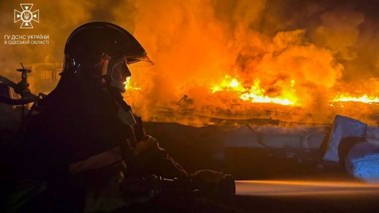 A firefighter, seen in profile, battles a massive fire.