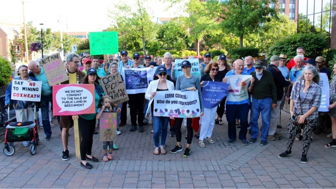 A group of people are gathered and holding signs with slogans such as "Say no to mining" and "Don't pollute the water".