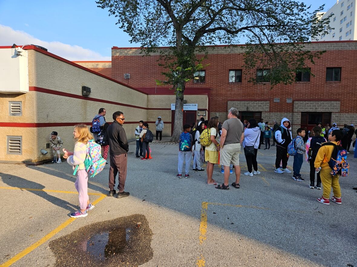 Children wait outside a school to enter on the first day of the school year.
