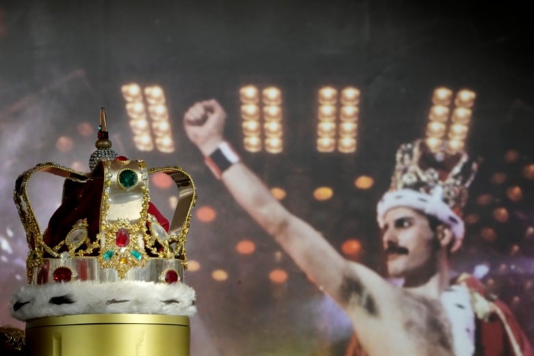 A bejewled crown on a stand beside a phot of Freddie Mercury