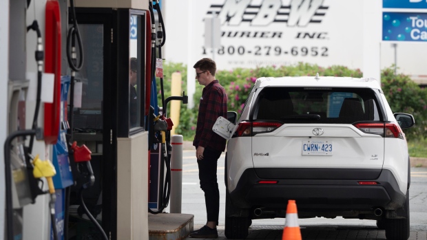 Canada's budget watchdog re-ran the numbers on the carbon tax — here's what it found; A motorist stands at the fuel pump to fill their tanks before the new federal carbon pricing takes effect at midnight in Halifax, Friday, June 30, 2023\. 