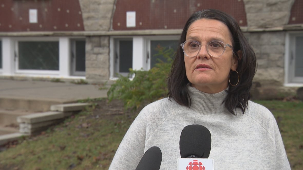 A woman speaking into a CBC microphone outdoors.