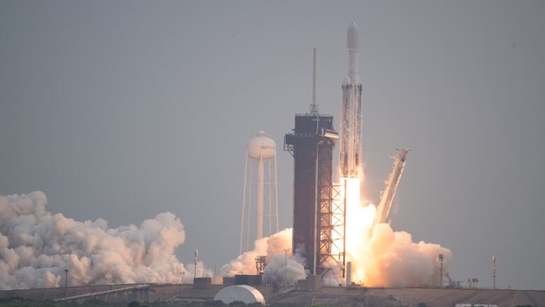 A rocket takes off from its launchpad against the backdrop of a blue sky.
