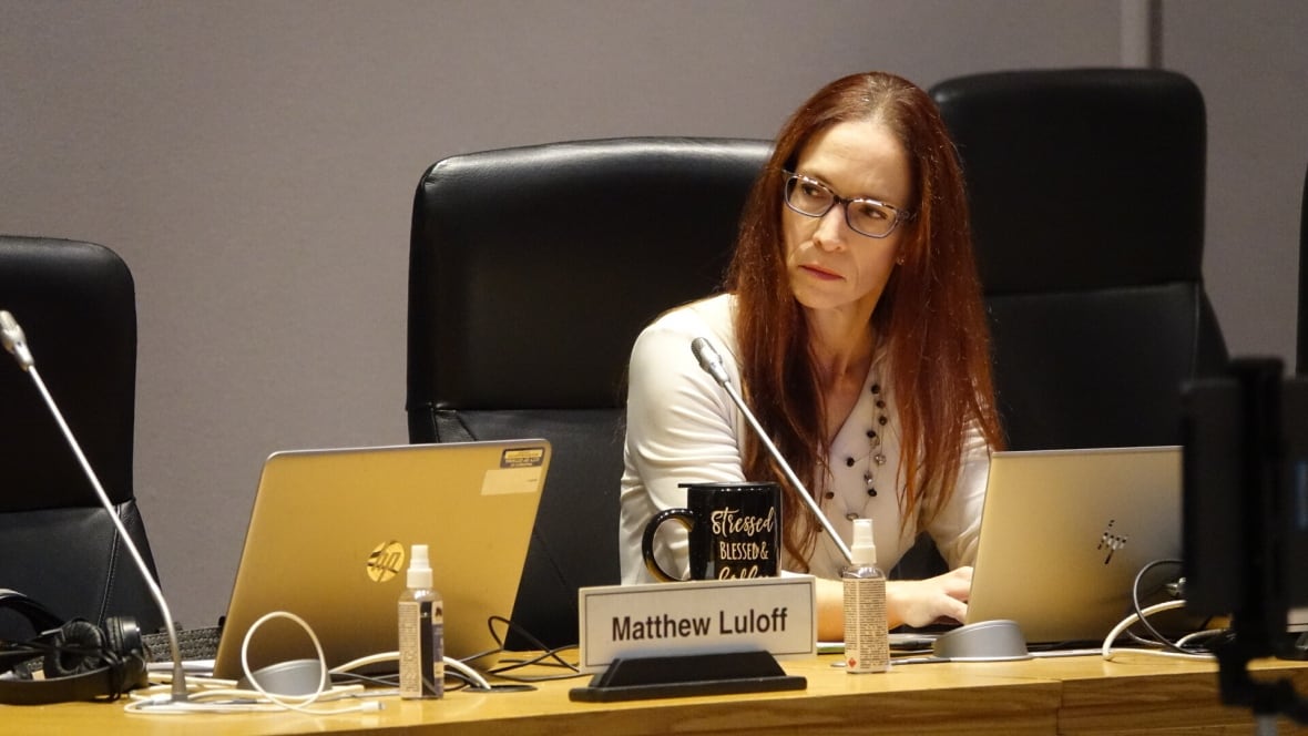 A city councillor listens at their desk during a meeting.