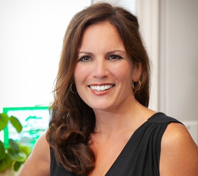 A woman with long, dark hair smiles for a photograph.