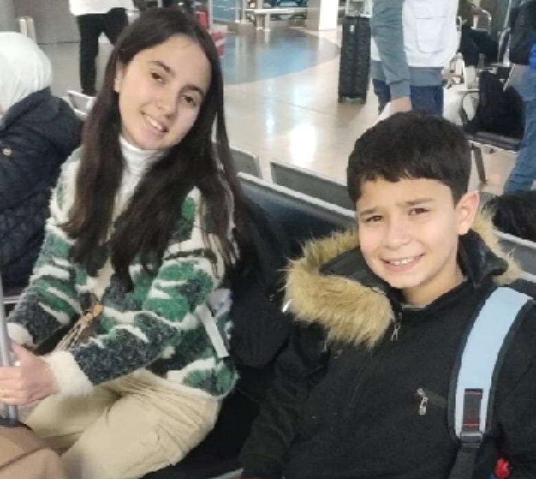 Two children sit in an airport.