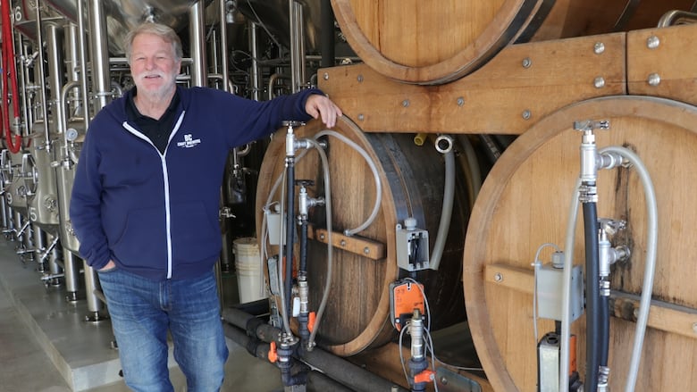 BC Craft Brewers Guild executive director Ken Beattie leans against large kegs of beer. He says craft breweries in the province are struggling to pay their bills and may be forced to close in 2024 when the CEBA deadline arrives.