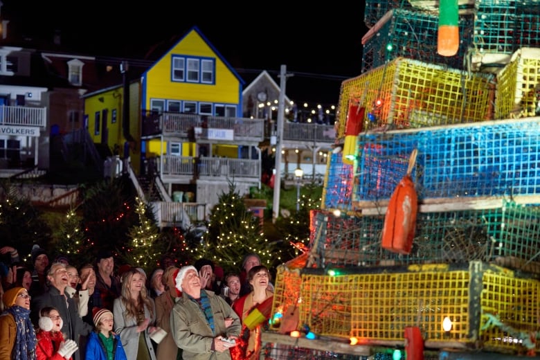 A crowd watches as a Christmas tree fashioned from lobster traps is lit up for the holiday season. 