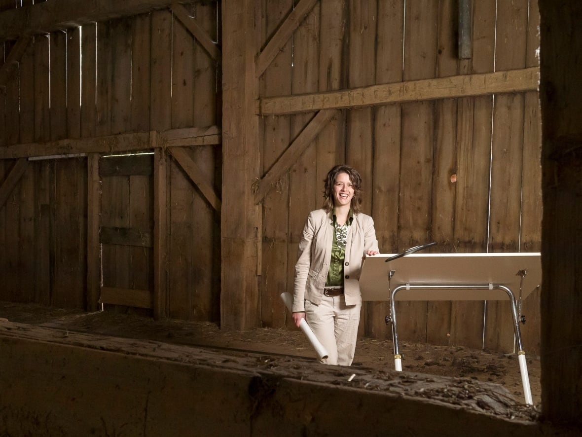 woman stands in barn smiling