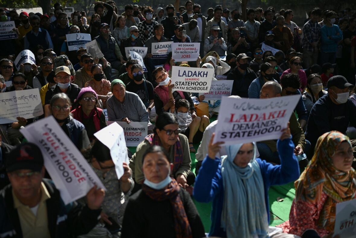 Dozens of people are shown outdoors at a demonstration, with some holding up signs that read, 'Ladakh demands statehood.'