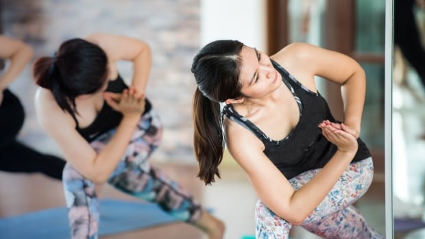 Two women do yoga in a studio. 