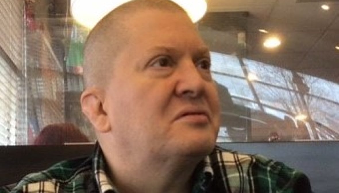 A middle-aged man with a shaved head looks off camera.