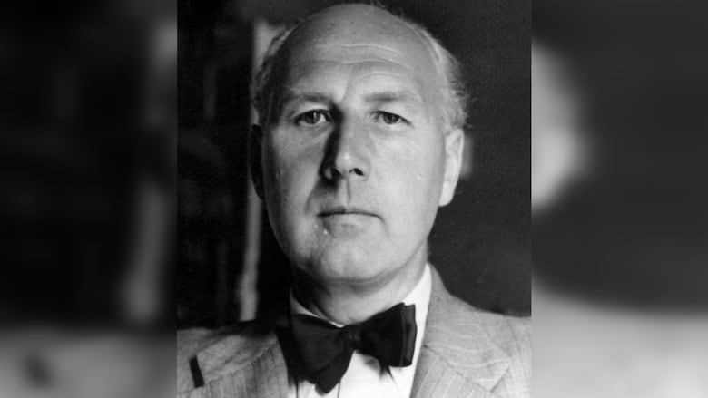 Black and white photo of a balding man with short, white hair. He has a bowtie and suit jacket. He is only seen from the shoulders and head.