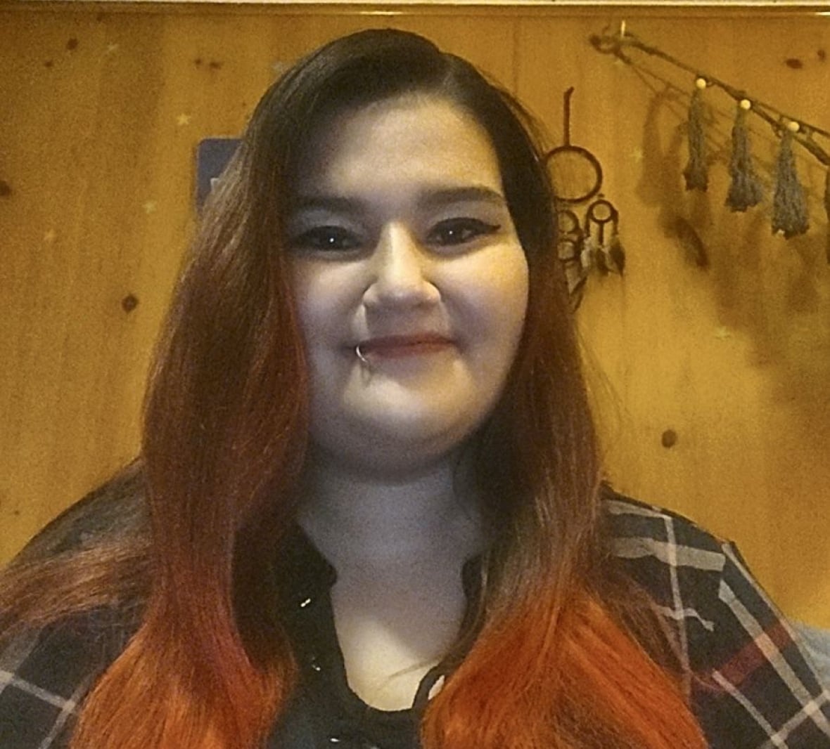 Woman smiles at camera with dream catchers in the background.