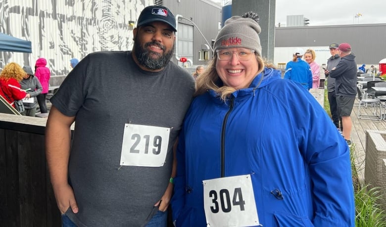 A Black man and a white woman at a race with numbers of their jackets.
