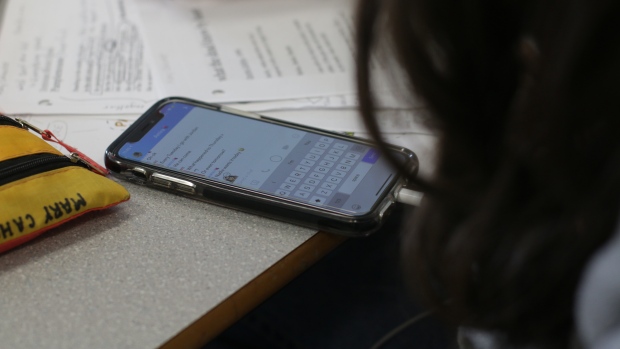 Clarity lacking on new cell rules in Ontario schools: critics; Teenagers are shown on cellphones, in closeup\. 