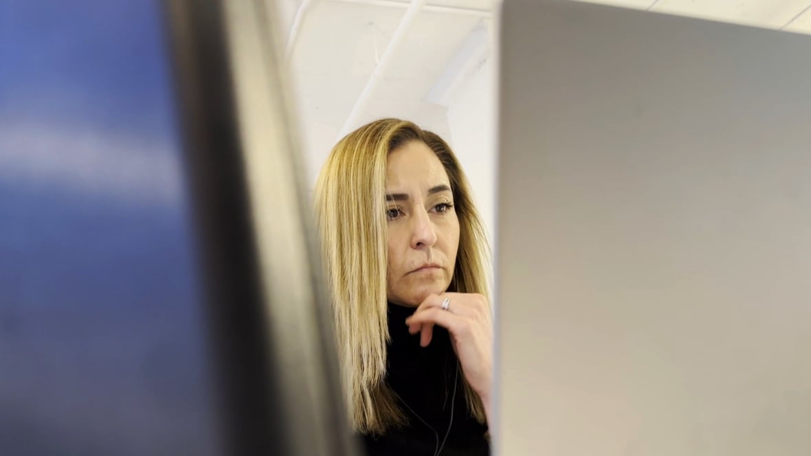A woman sitting at a computer looking at the screen.