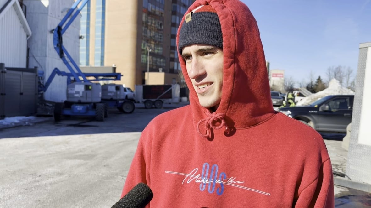 A man wearing a hoodie and talking into a microphone.