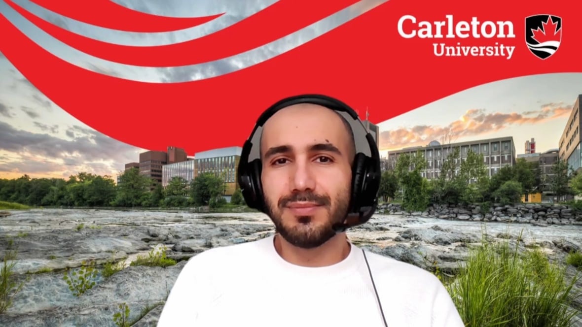 Man with headphones on in front of a university backdrop.
