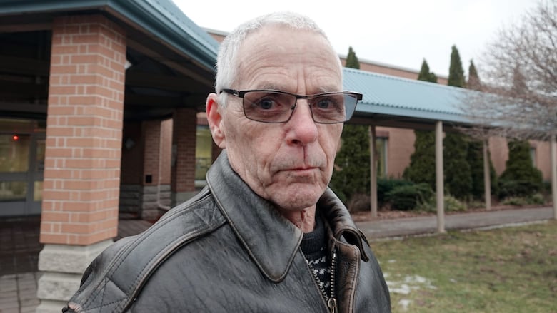 A man in glasses stands outside.