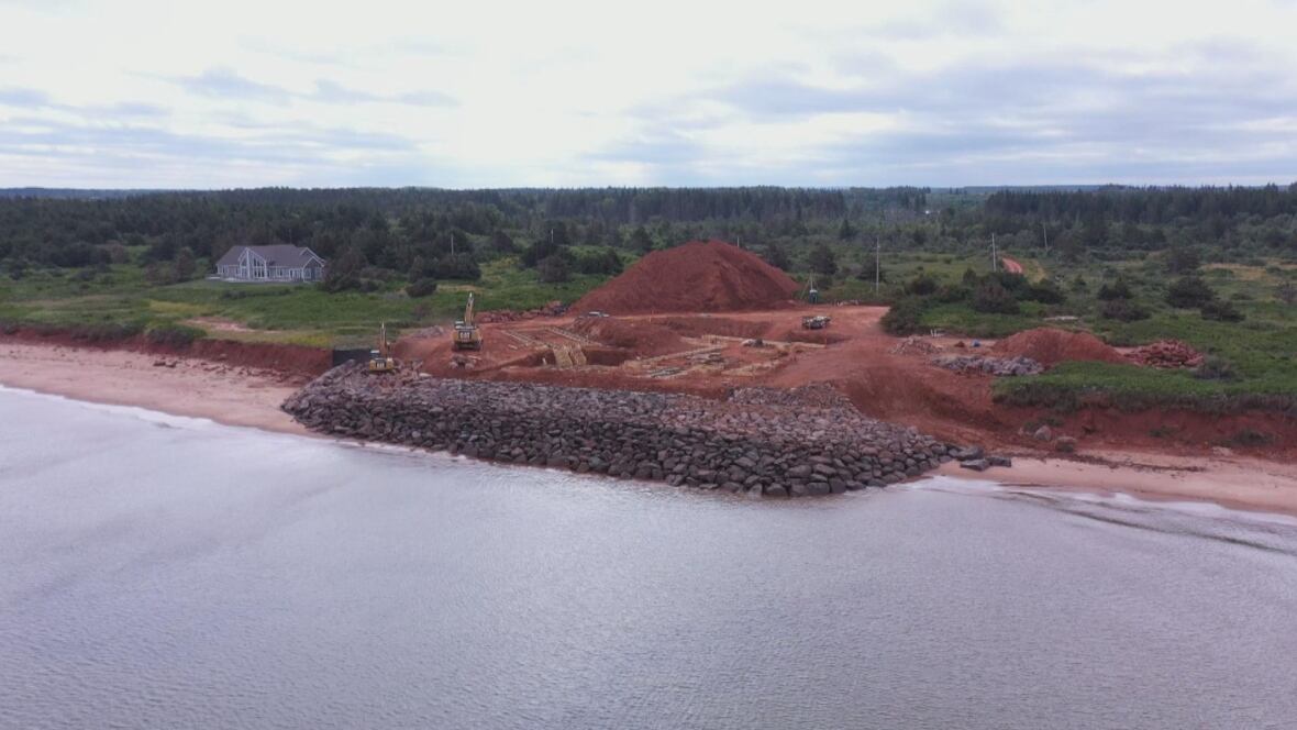 Stone armoring is seen on a piece of shorefront property surrounded by trees.