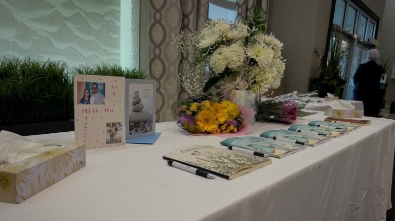 Guest books, flowers and cards are placed on a white table.